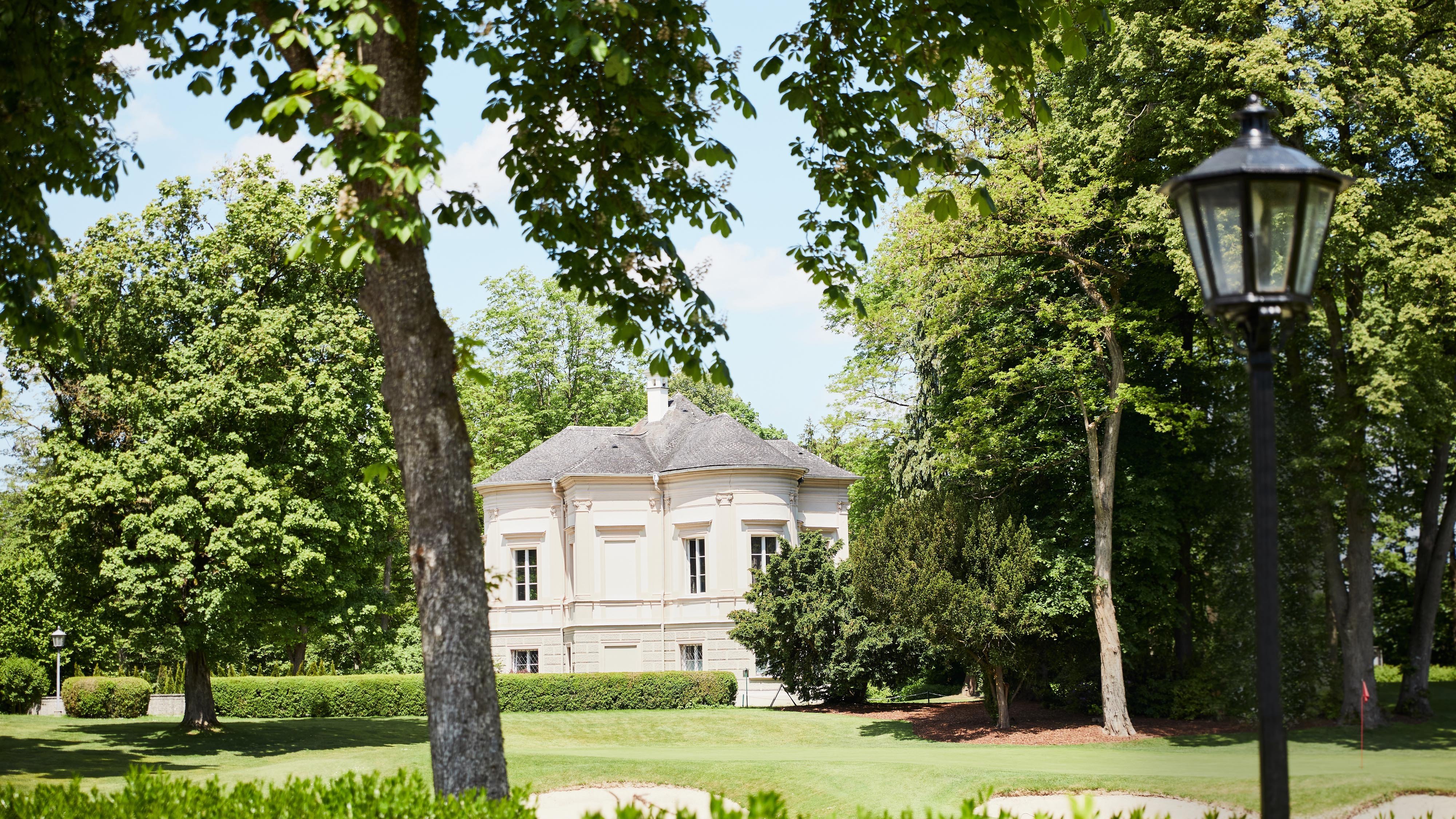 Blick auf das Clubhaus des Golf & Country Club Salzburg-Klessheim, umgeben von Natur und Grünflächen