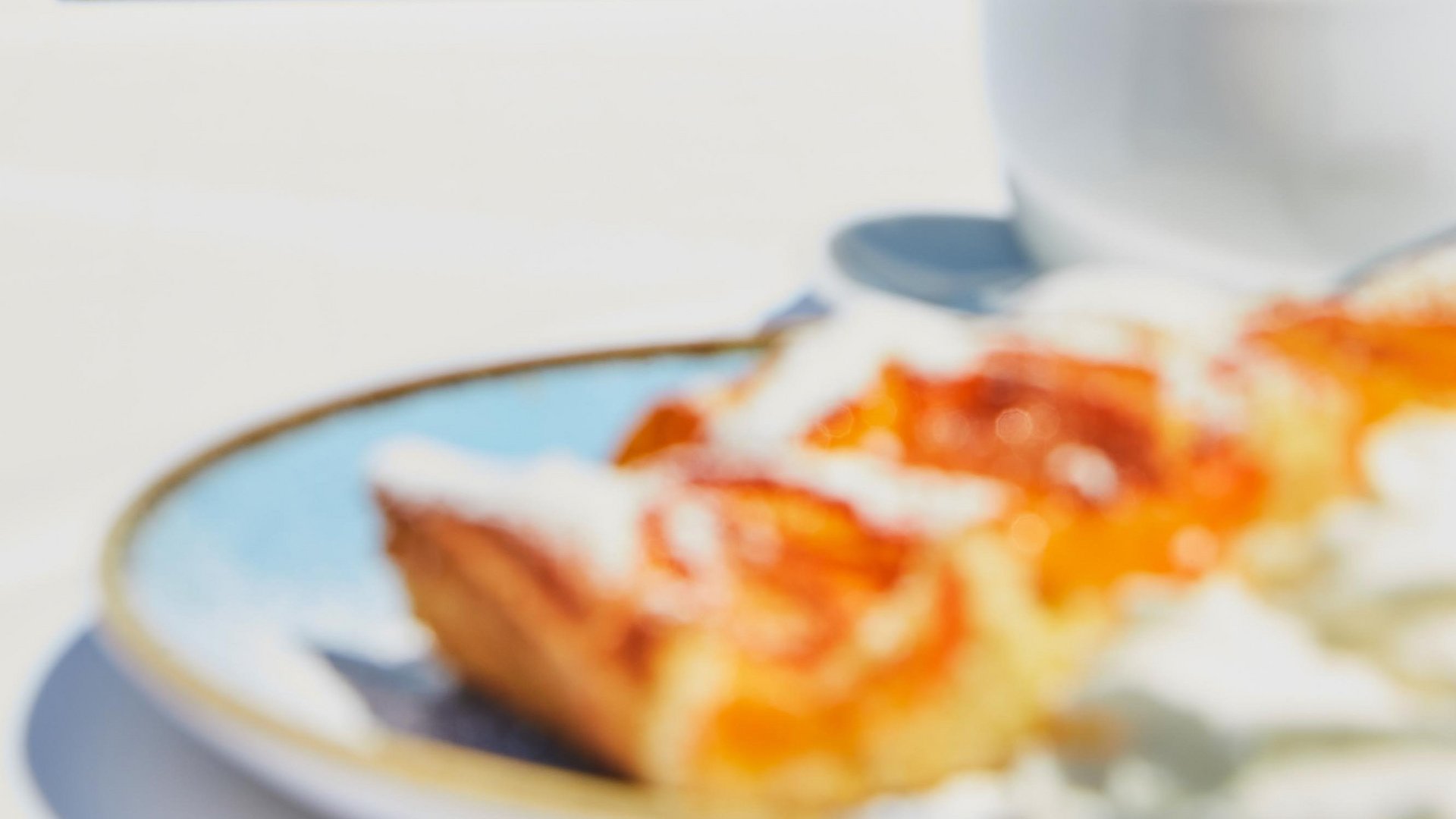 Marillenkuchen mit Schlagsahne und eine Tasse Kaffee auf der Terrasse des Hubers Restaurants mit Blick auf die Golfanlage