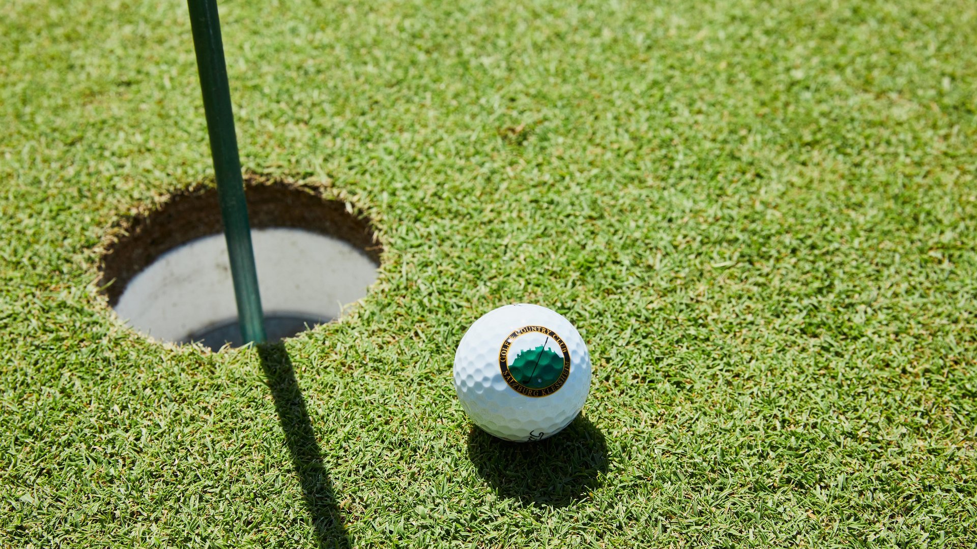 Golf ball in front of the hole on the lawn at Klessheim Golf Club